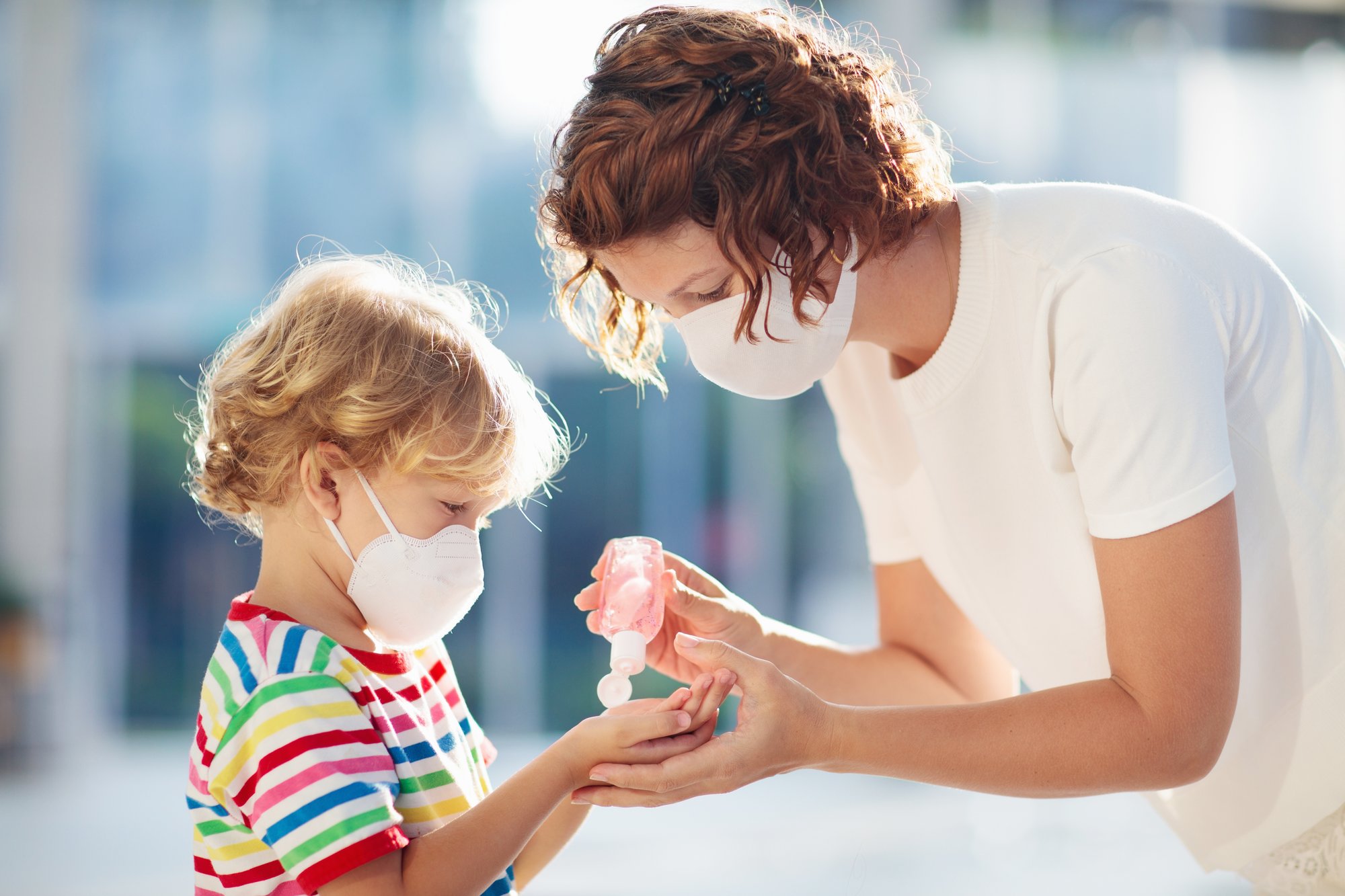 A woman giving a child sanitizer. 