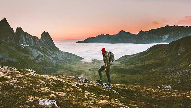 Man hiking at sunset mountains with heavy backpack