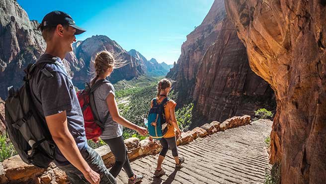 Group of hikers friends walking down the stairs and enjoying view of Zion National Park, USA