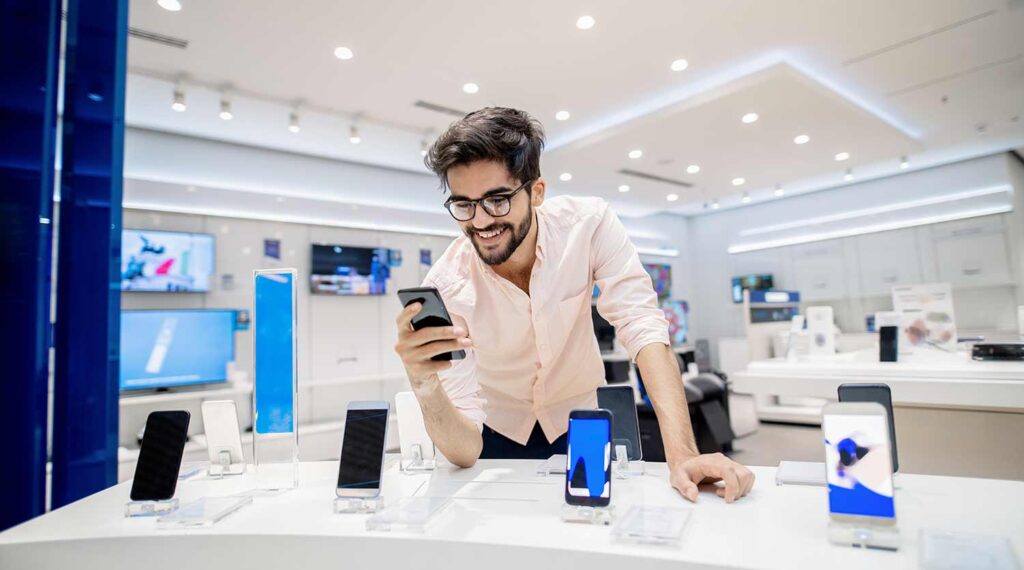 Young man browses a selection of smartphones in an electronics store