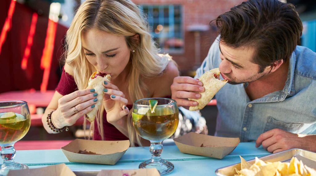 Couple enjoys tacos at a table outside