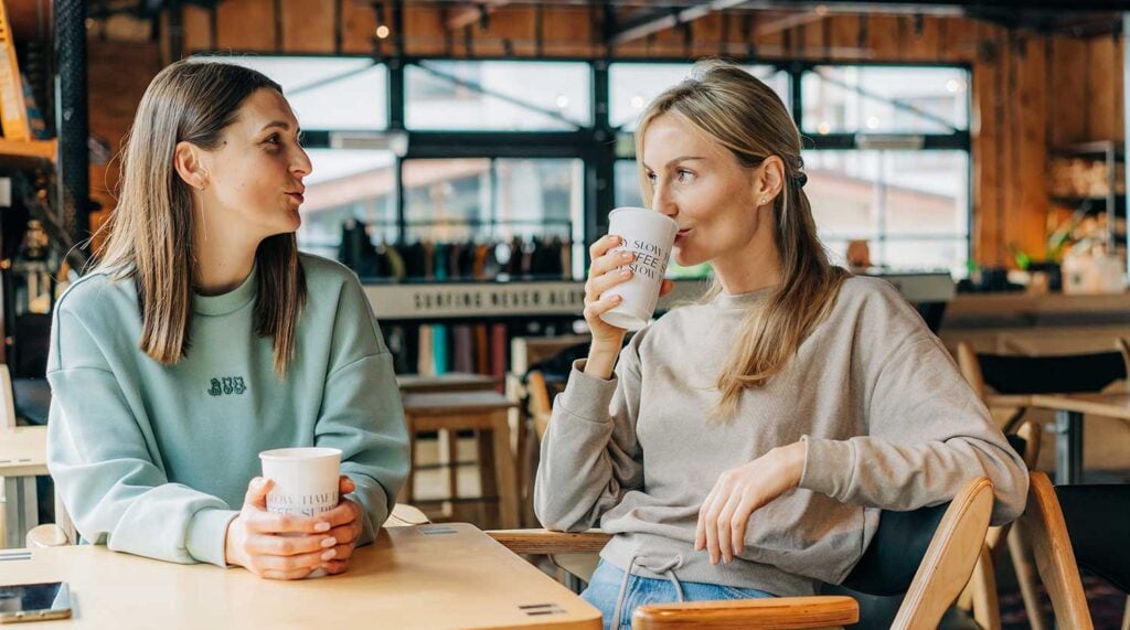 Two female friends enjoy a coffee inside.