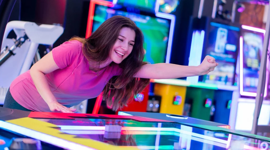 Young woman enjoys herself playing a game in an indoor arcade.
